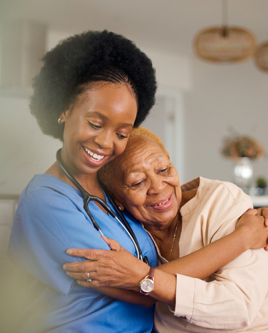 Caregiver and older woman cooking together in a warm kitchen.