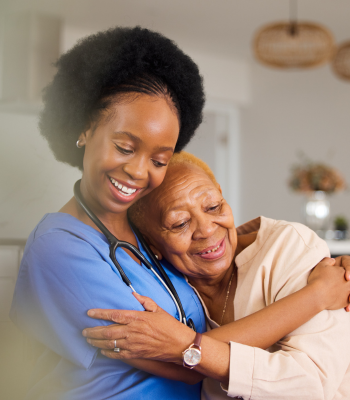 Caregiver hugging an older woman after a first successful day of in-home care.